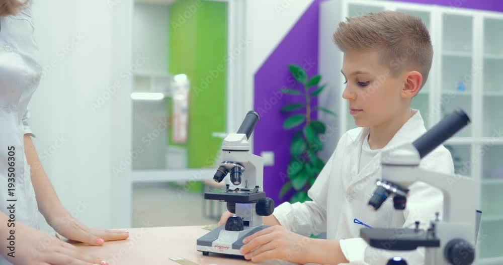Teacher and student prepare a microscope, adjust the microscope for work Teacher and student prepare a microscope, adjust the microscope for work