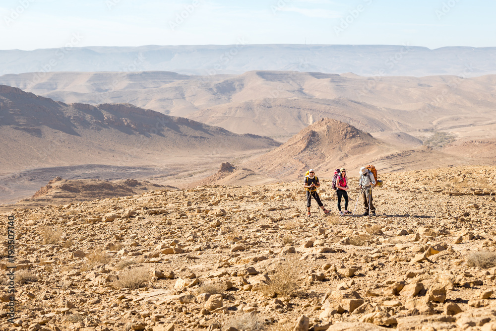 Three backpackers standing mountains trail , Negev desert,  Israel.