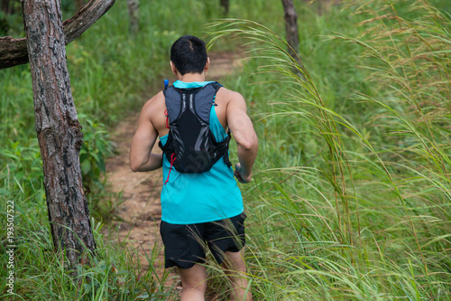 Athletic runner running on tropical forest trail, dramatic tone