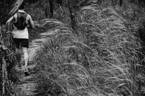 Athletic runner running on tropical forest trail, dramatic tone