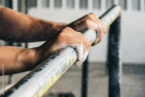 Closeup of male hand with powder on horizontal bar. Pull ups exercise.
