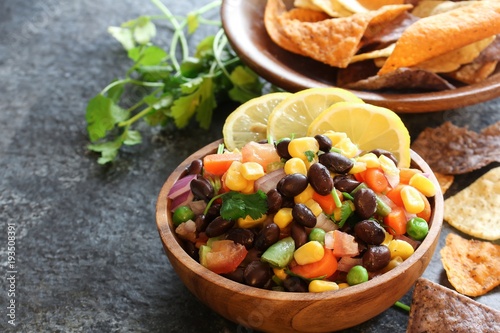Homemade black bean corn salsa with chips served in a wooden bowl, selective focus
