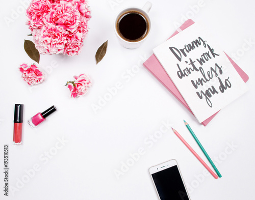 Woman fashion home office desk workspace with handwritten quote notebook, pink carnation flowers, coffee cup, smartphone and cosmetics on white background. Flat lay. Top view. Stylish female concept.