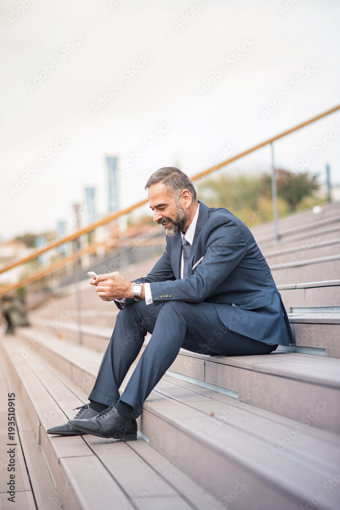 Senior businessman relaxing in an urban area, having a break from work