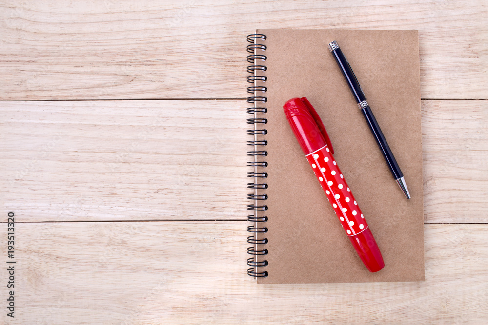 Book with red marker pens and black pen on wooden background Book with red marker pens and black pen on wooden background