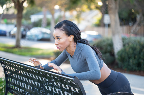 Gorgeous black woman athlete working out at the bench in the par
