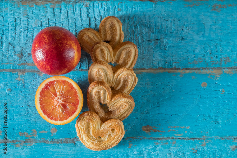 heart shaped cookies and red orange on a blue wooden surface with a place for text, toned heart shaped cookies and red orange on a blue wooden surface with a place for text, toned