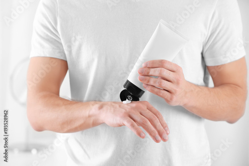 Man applying body cream at home, closeup