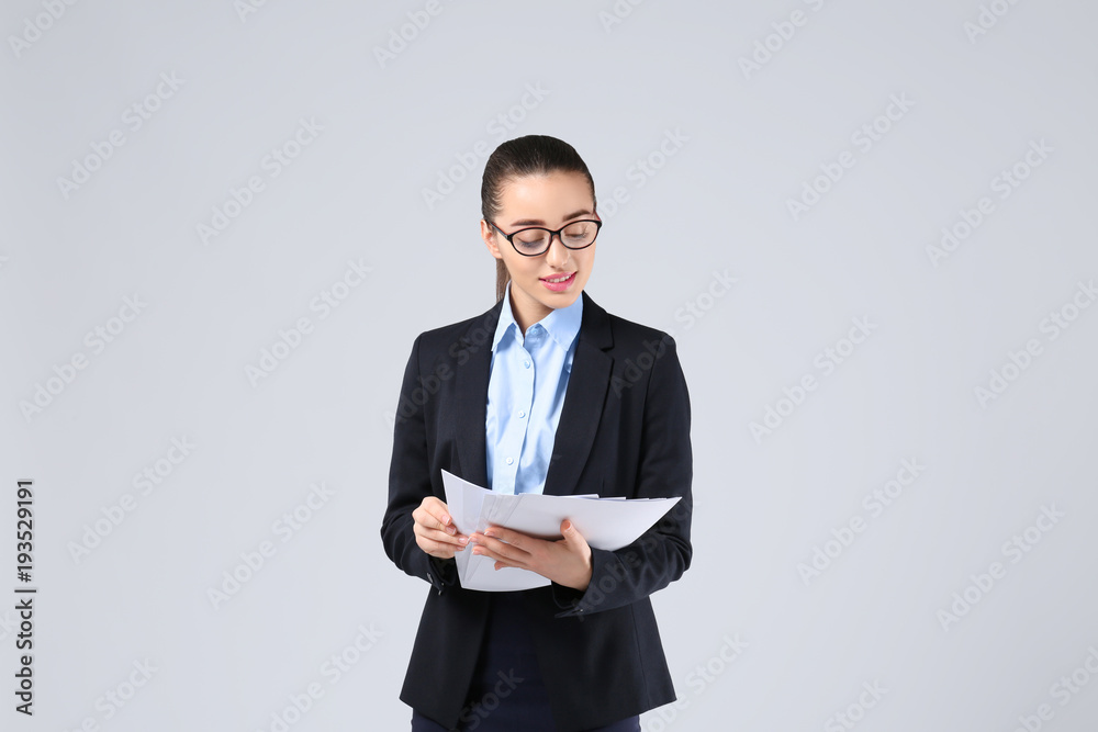 Beautiful young businesswoman in elegant suit and with documents on light background Beautiful young businesswoman in elegant suit and with documents on light background
