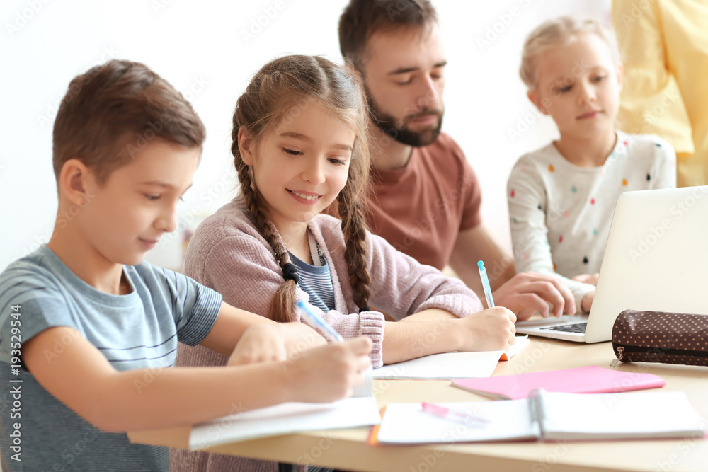 Children doing homework with teacher in classroom at school Children doing homework with teacher in classroom at school