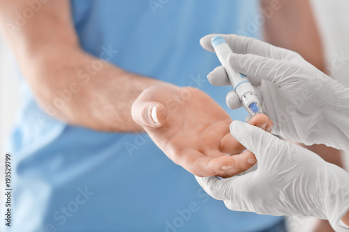 Doctor taking sample of diabetic patient s blood using lancet pen  closeup