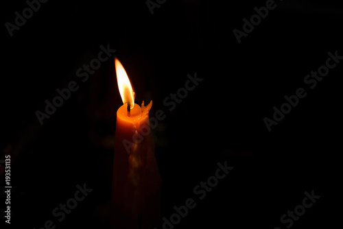One yellow candle burning brightly in black background