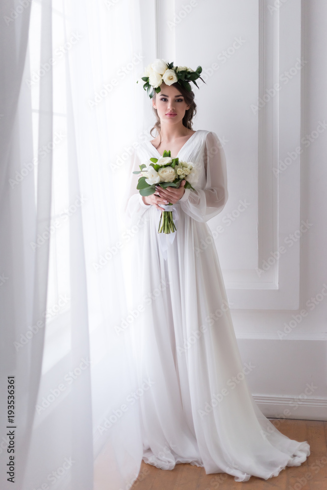 attractive bride in traditional dress and floral wreath holding wedding bouquet attractive bride in traditional dress and floral wreath holding wedding bouquet