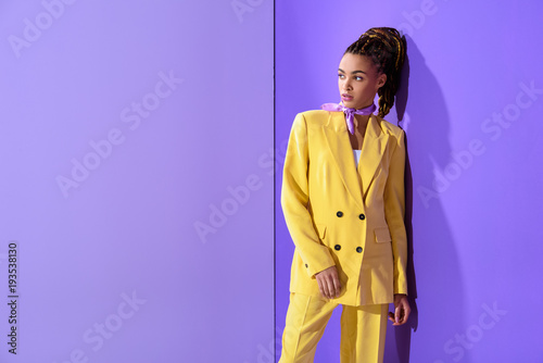 african american girl posing in yellow suit, on trendy ultra violet background