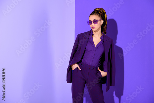 stylish african american girl posing in purple suit and sunglasses, ultra violet trend
