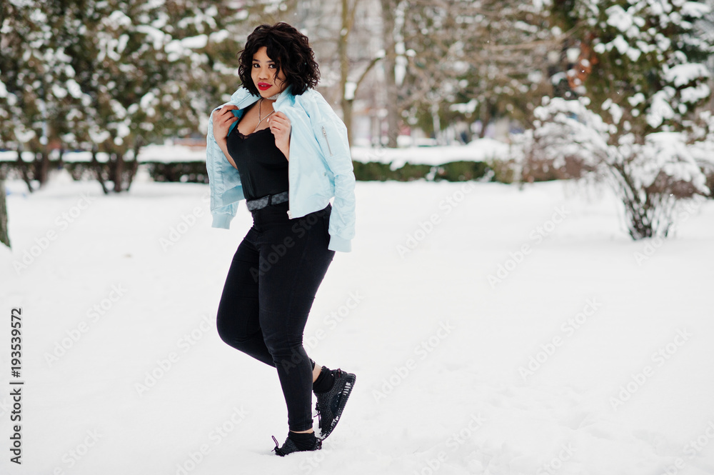 Stylish african american plus size model with mobile phone at hand at winter snowy day. Stylish african american plus size model with mobile phone at hand at winter snowy day.
