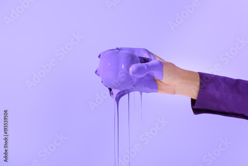 cropped view on woman holding apple in purple paint, isolated on ultra violet
