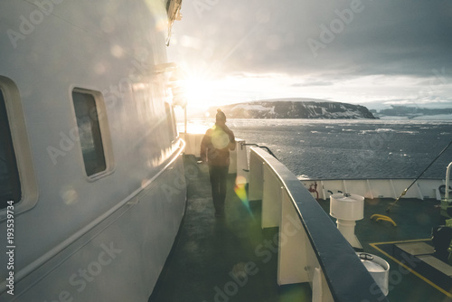 Man walking on a Ship towards the Sun - Antarctica.