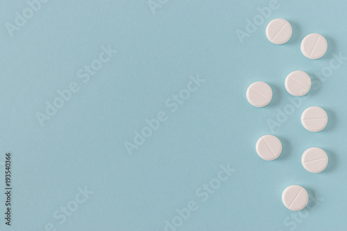 White pills on the bright blue surface. Top view.