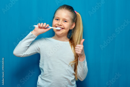 Smiling girl holding three toothy brush.