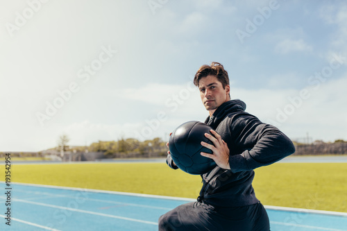 Athlete training with a medicine ball on running track