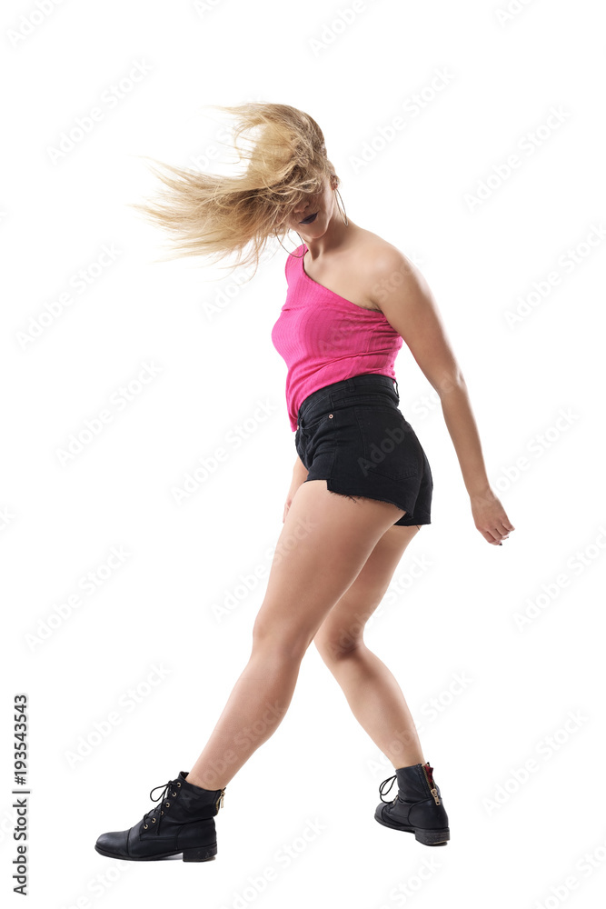 Profile of funky trendy blonde woman dancing and turning at camera with tousled hair. Full body length portrait isolated on white studio background. Profile of funky trendy blonde woman dancing and turning at camera with tousled hair. Full body length portrait isolated on white studio background.