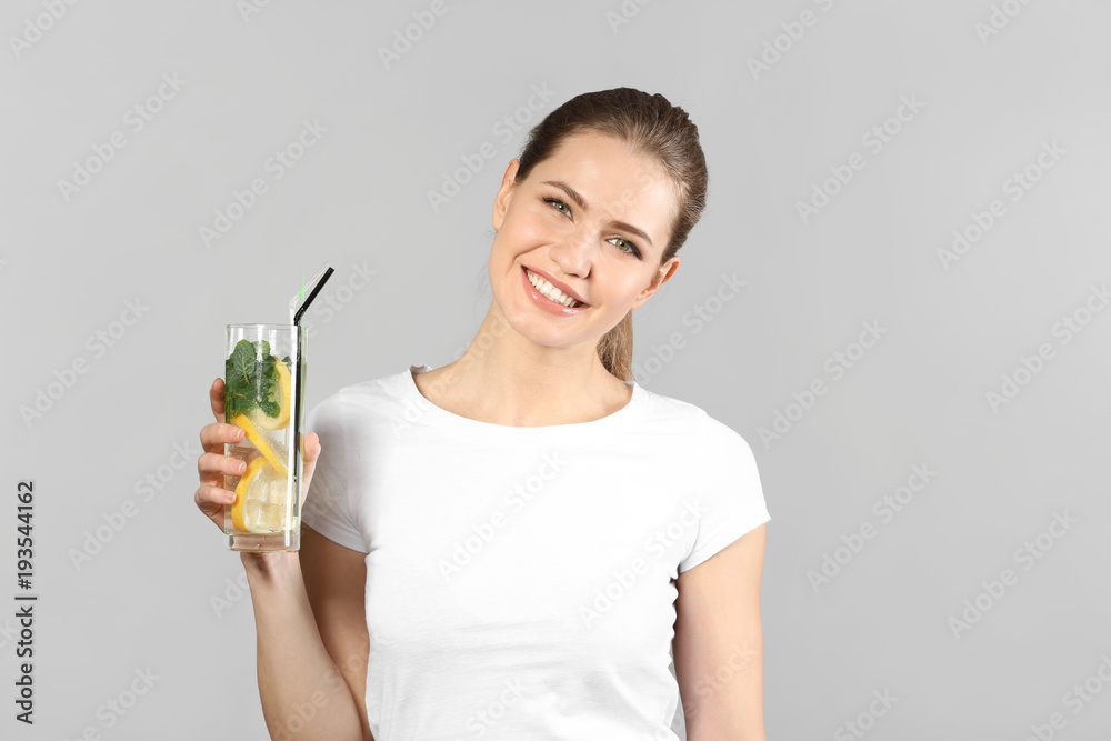 Beautiful young woman with glass of lemonade on grey background Beautiful young woman with glass of lemonade on grey background