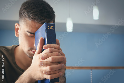 Quadro su tela Religious young man with Bible praying at home