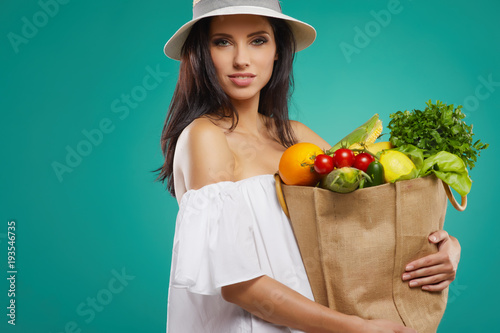 Isolated woman holding a shopping bag full of vegetables