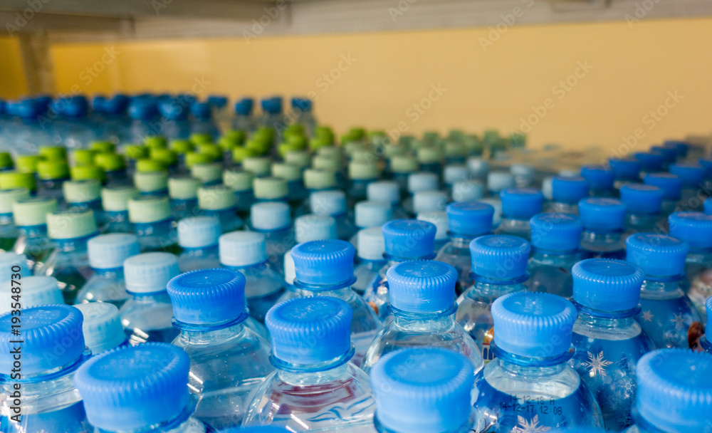 Plastic bottles with mineral water. Closeup on water bottles in raw and lines. Plastic bottles, colorful caps. Plastic bottles with water, lids. Plastic bottles with mineral water. Closeup on water bottles in raw and lines. Plastic bottles, colorful caps. Plastic bottles with water, lids.