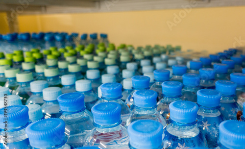Plastic bottles with mineral water. Closeup on water bottles in raw and lines. Plastic bottles, colorful caps. Plastic bottles with water, lids.