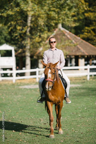 Elegant casually dressed man riding a horse 