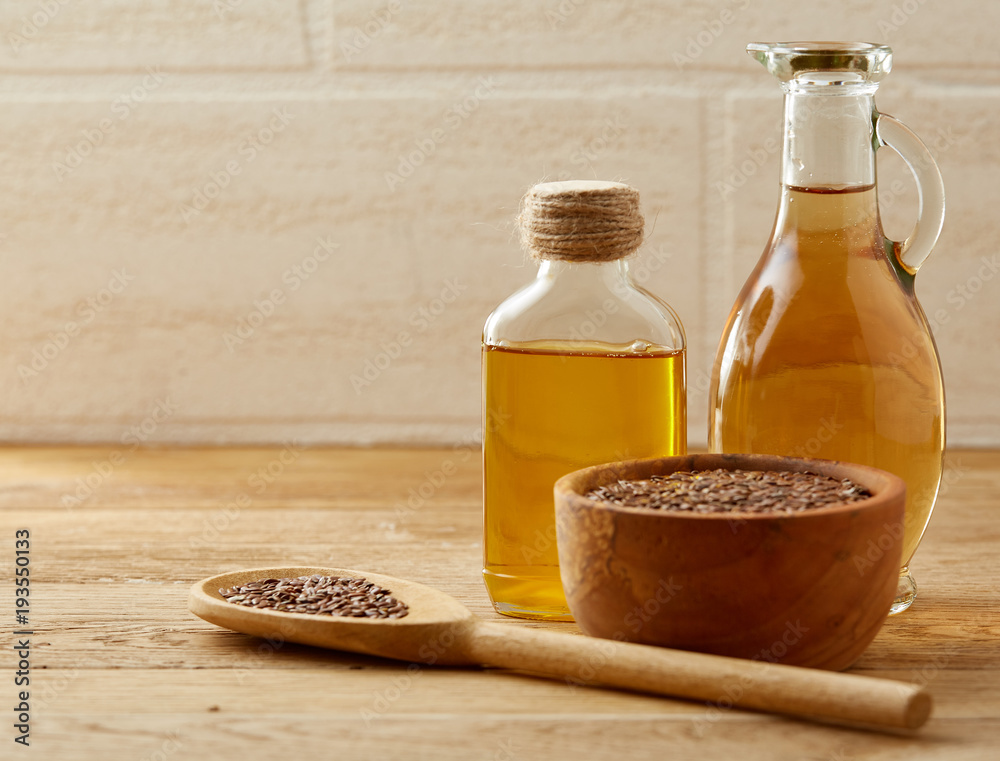 Flax seeds in bowl and flaxseed oil in glass bottle on wooden background, top view, close-up, selective focus Flax seeds in bowl and flaxseed oil in glass bottle on wooden background, top view, close-up, selective focus
