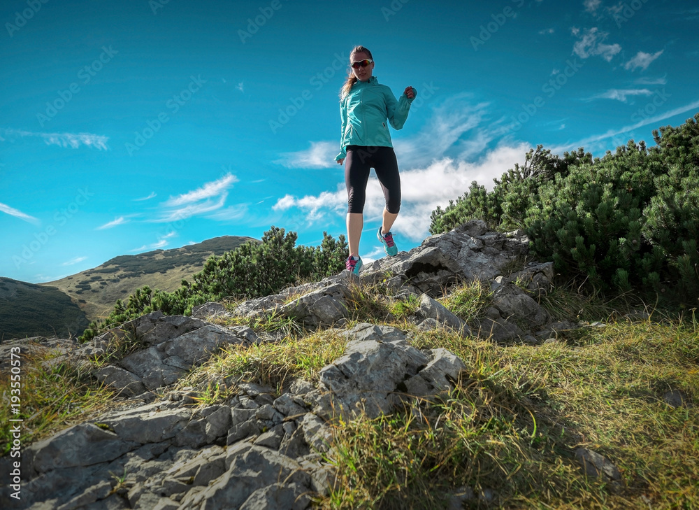 Female running in mountains under sunlight.