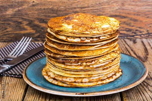 High stack of hot pancakes on wooden table