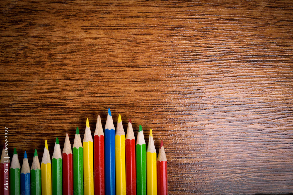 Different colored pencils on the brown wooden table background .Top view .Close up .Color .Pencil.Set Different colored pencils on the brown wooden table background .Top view .Close up .Color .Pencil.Set
