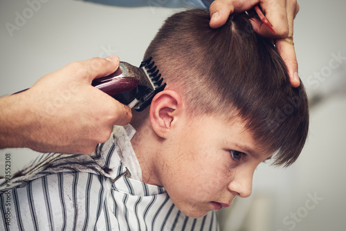 Fotografie Caucasian boy  getting haircut in barbershop.