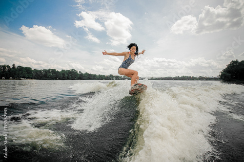 woman riding stylish pink wakeboard on high wave