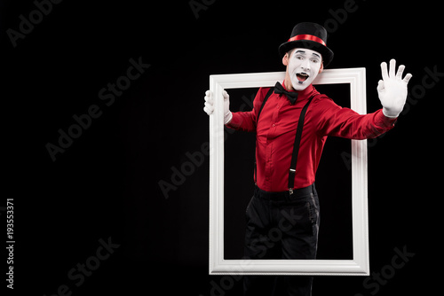 happy mime waving hand from frame isolated on black photo