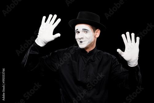 smiling mime performing and touching something isolated on black