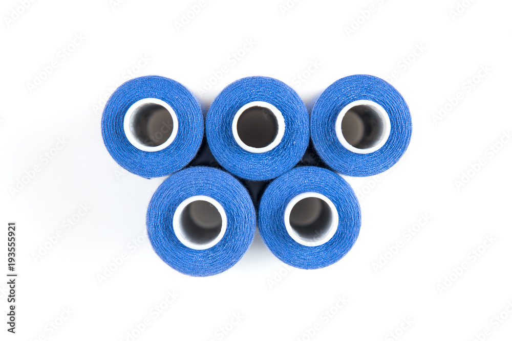 Five blue sewing threads on a white coils on a white background. Sewing supplies Five blue sewing threads on a white coils on a white background. Sewing supplies