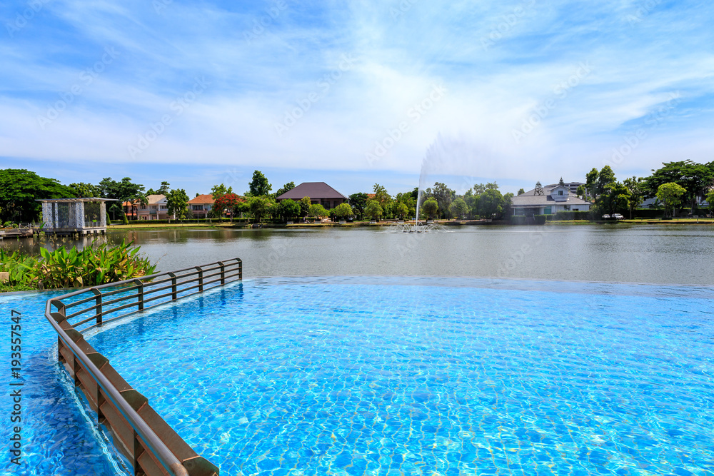 Beautiful outdoor swimming pool beside village lake with clear sky and cloudy.