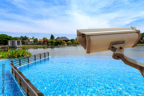 CCTV security camera secure to protect and outdoor swimming pool and lake with beautiful sky. Copy space.