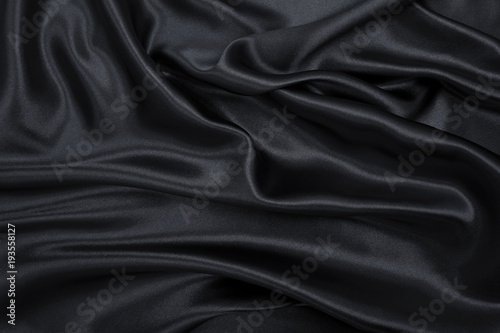 Smooth elegant black silk or satin texture as abstract background. Luxurious background design