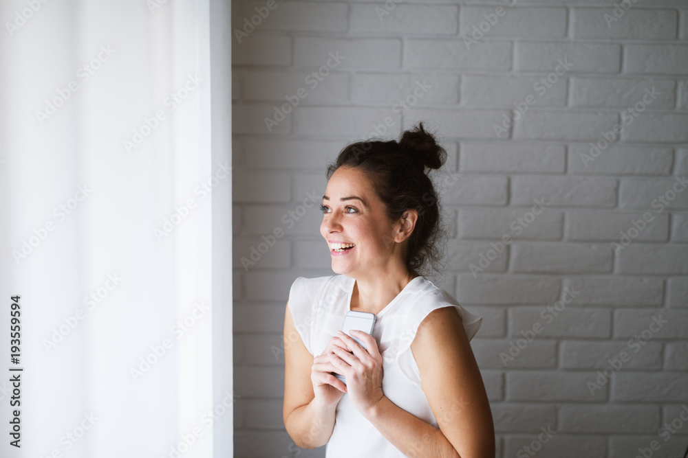 Joyful middle aged woman holding mobile phone smiling. Joyful middle aged woman holding mobile phone smiling.