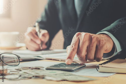 accountant using calculator to calculate of money budget on desk in office. business finance and accounting photo