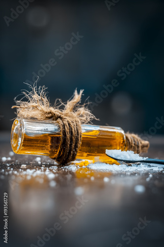 Close up of aurvedic herb camphor powder in a small spoon and its oil on brown wooden surface in dark Gothic colors is helps in Prevents Skin Infections,Eliminates Gas,Reduces Nervous Disorders etc. photo