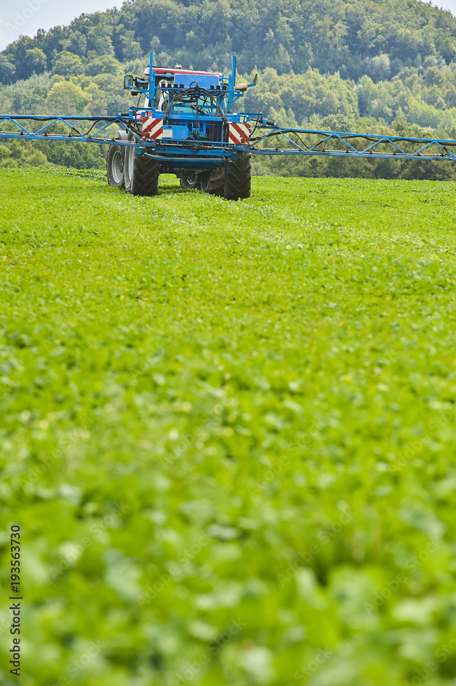 Tractor spraying pesticides on field with sprayer at spring Tractor spraying pesticides on field with sprayer at spring