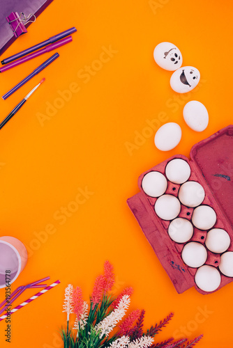 top view of chicken eggs in egg tray and felt tip pens for easter painting isolated on orange
