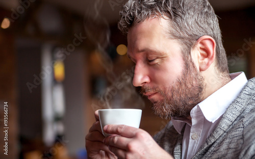 Middle age man smelling aroma of coffee in cafe